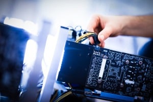 Man's hand plugging a wire in an input.